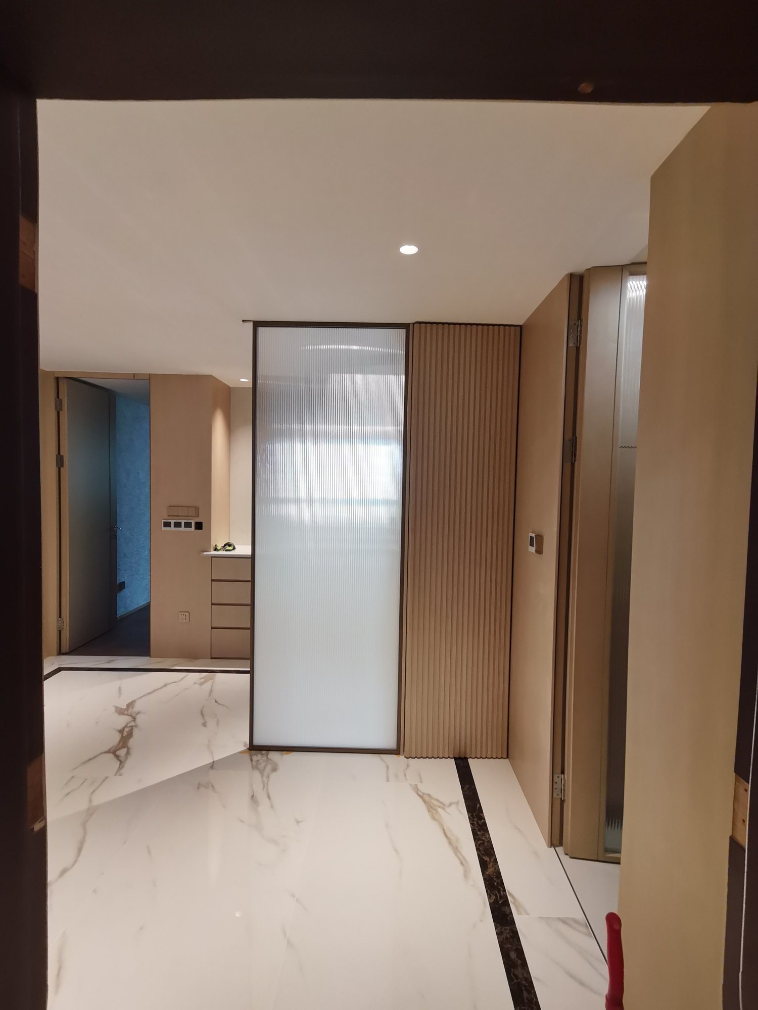 Entryway reeded glass partition with slatted wood wall panels and cabinetry
