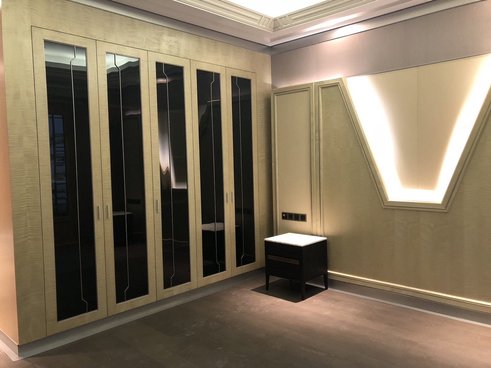 Bedroom custom wardrobe with decorative glass doors and paneling.