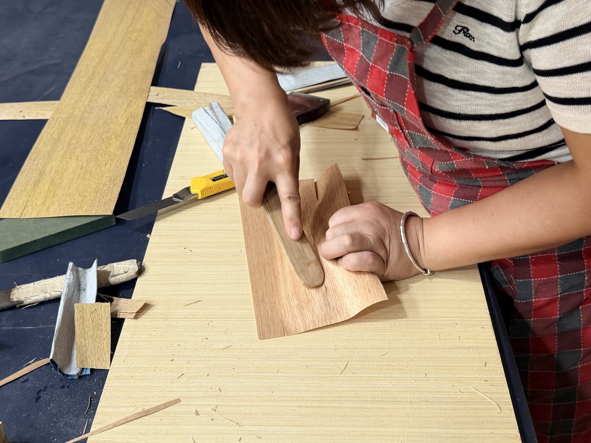 Hands manually aligning wood veneer sheets