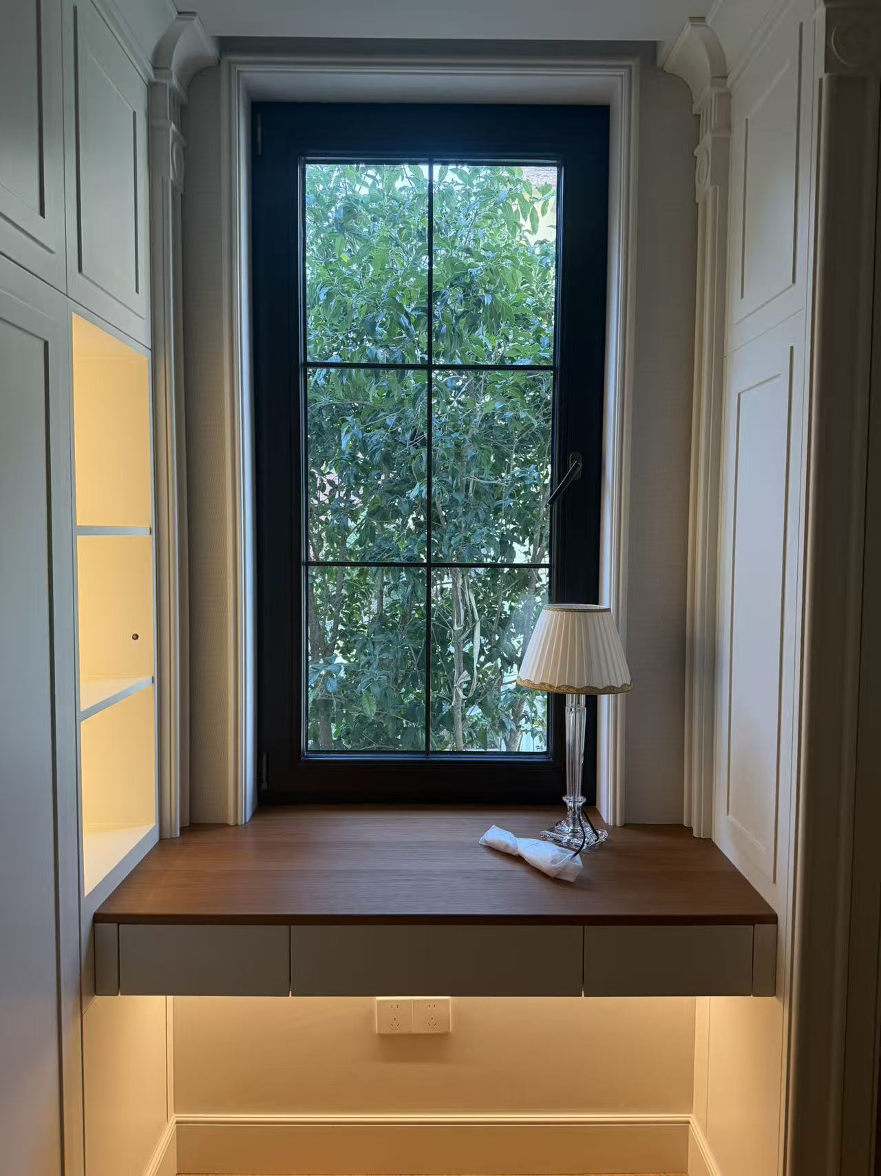 Study with custom desk by the window and illuminated cabinetry