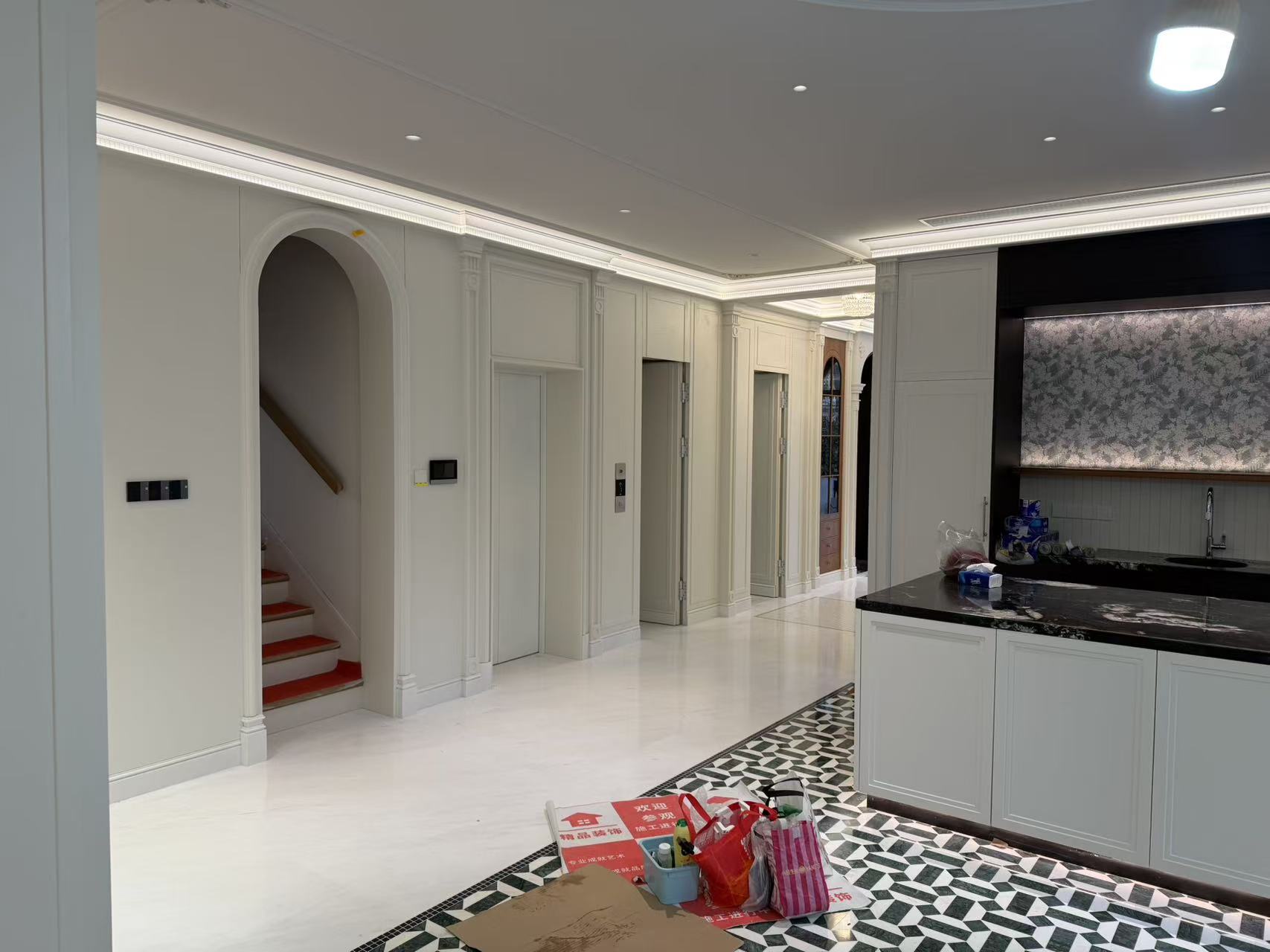 Living room with paneled staircase and kitchen island cabinetry