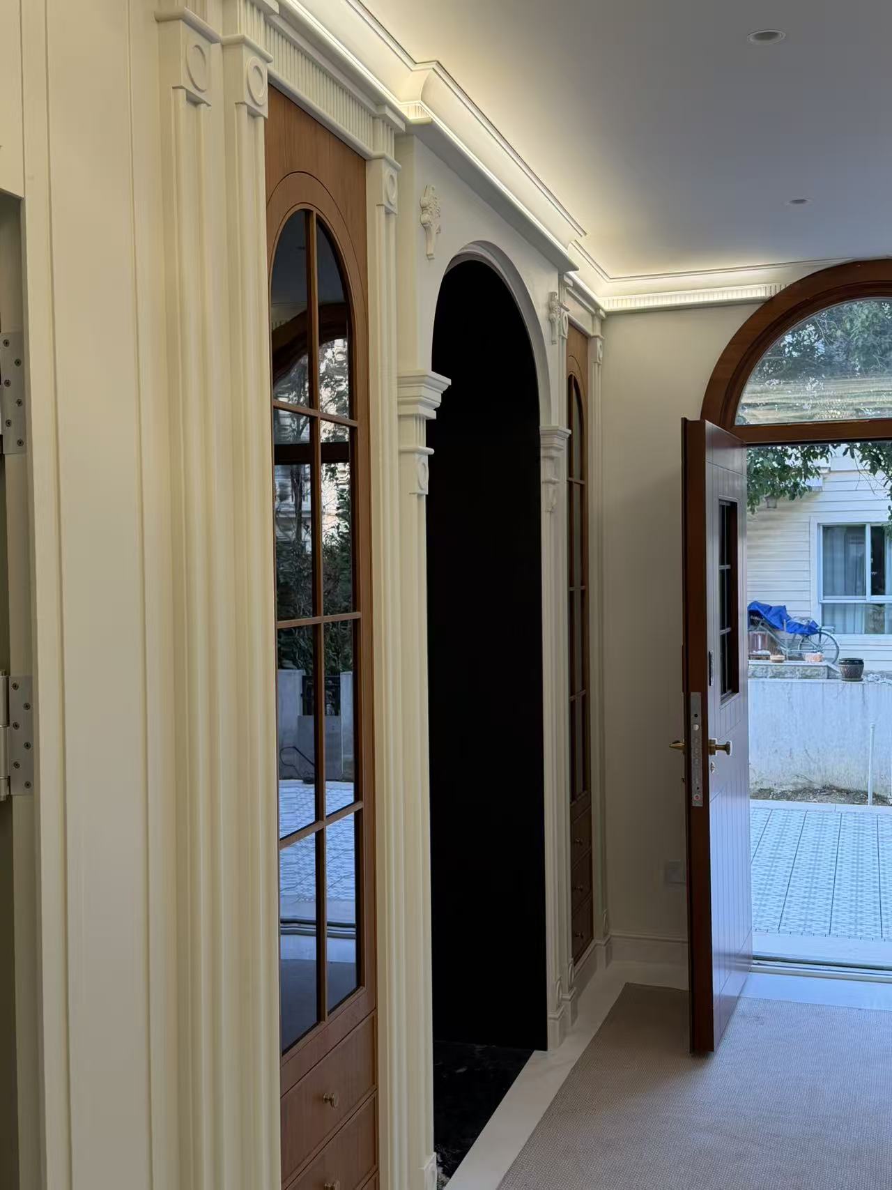 Entryway with arched glass door and Roman-column display cabinet