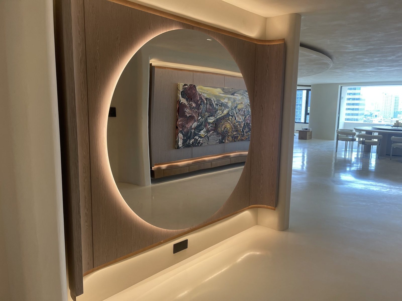 Living room round mirror and ambient-lit wood wall paneling
